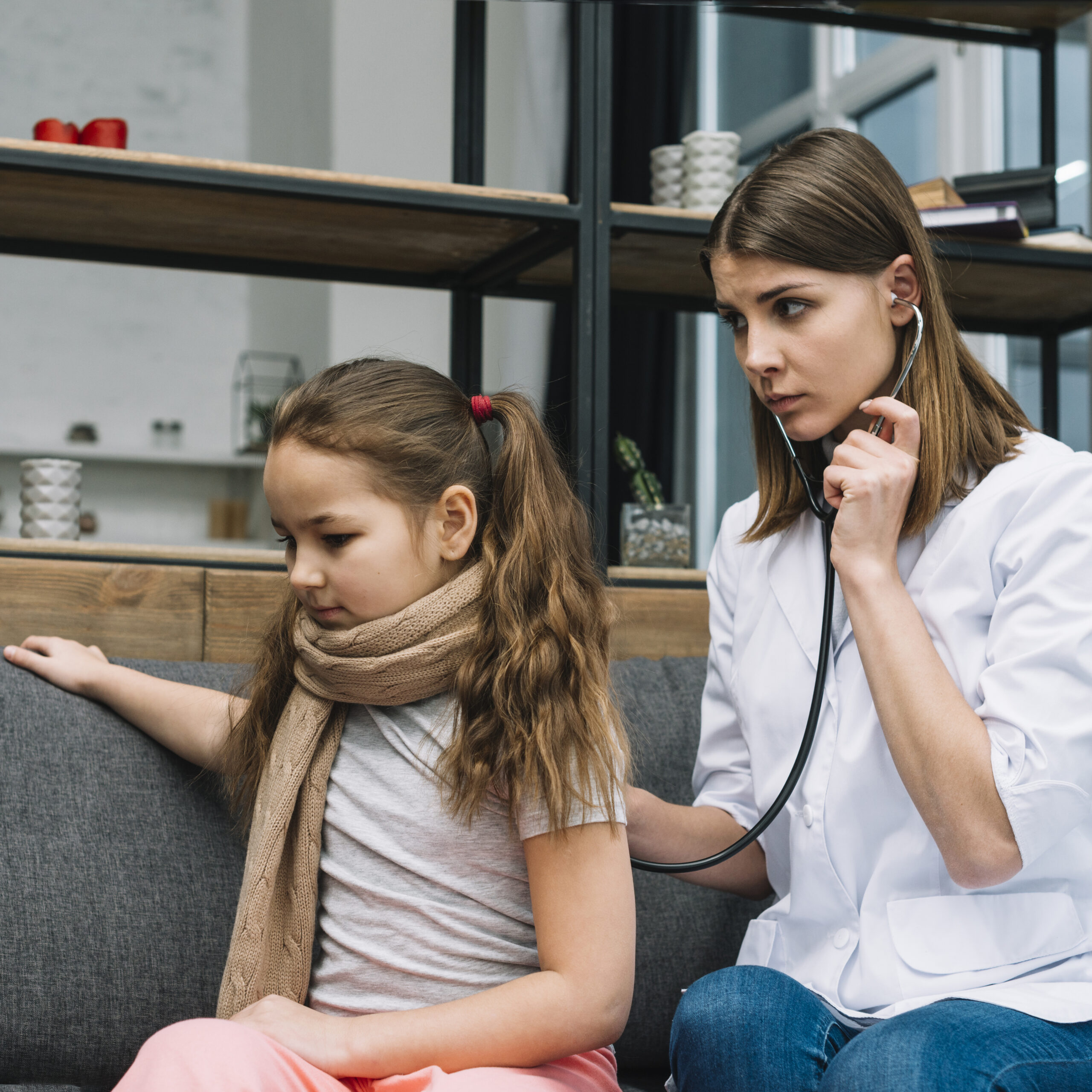 serious female doctor examining sick girl with stethoscope 1 scaled